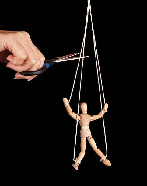 Hand cutting the strings of a puppet, giving it freedom